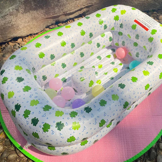 Baignoire Bébé Gonflable avec Motifs de Grenouilles en extérieur sur un tapis rose avec des balles à l'intérieur